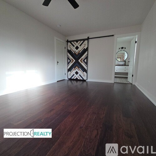 A room with wooden flooring and a patterned wallpaper.