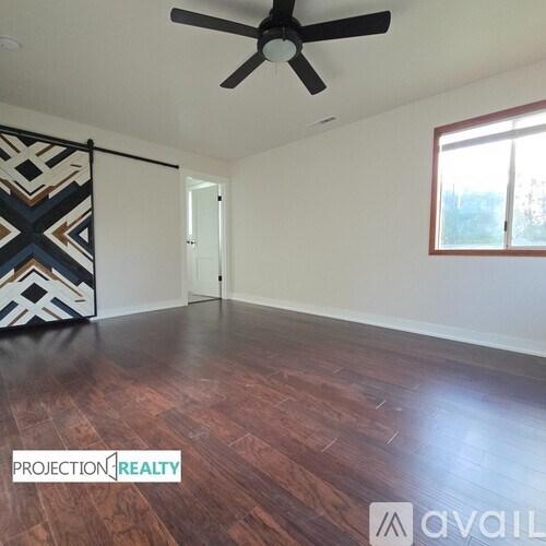 A room with a ceiling fan and wooden flooring.
