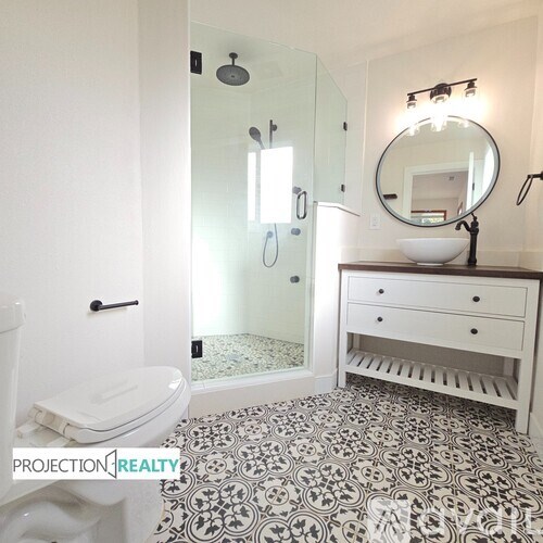 A bathroom with a toilet, sink, and mirror.