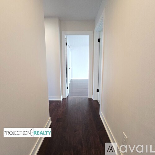 A hallway with wood floors and white walls.