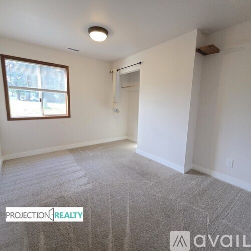 A room with a window and a carpeted floor.