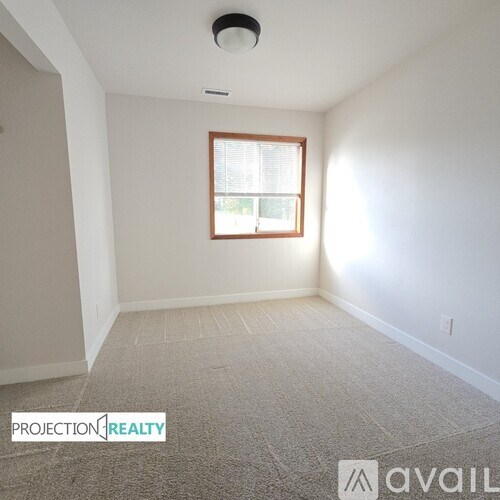 A room with a window and a carpeted floor.