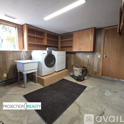 A laundry room with a washer and dryer, a sink, and cabinets.