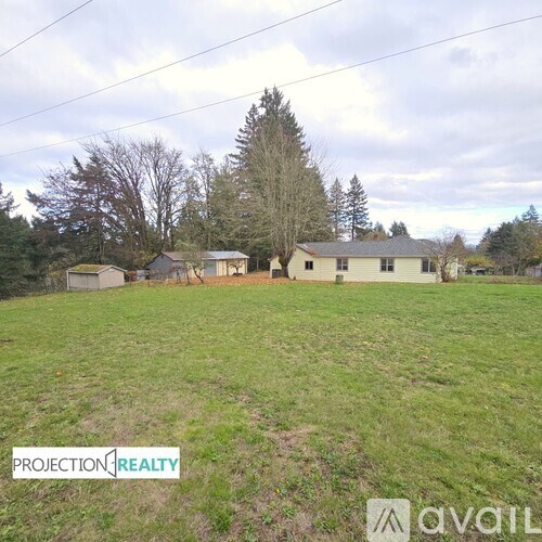 A grassy field with a house and trees in the background.