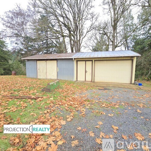 A shed with a metal roof and a closed beige garage door.