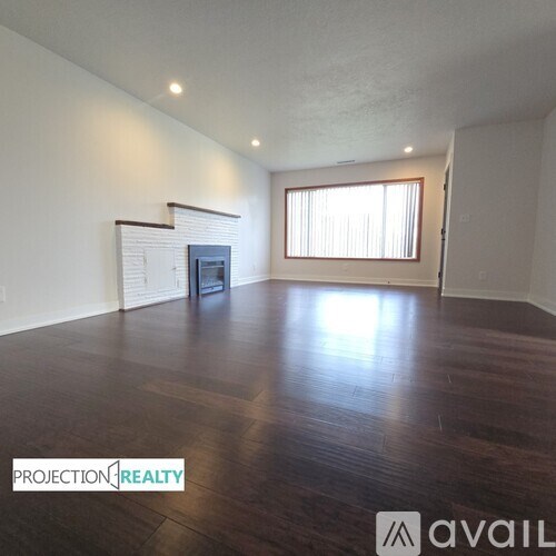 A spacious room with wooden floors and a fireplace.