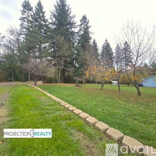 A grassy area with a stone path and trees in the background.
