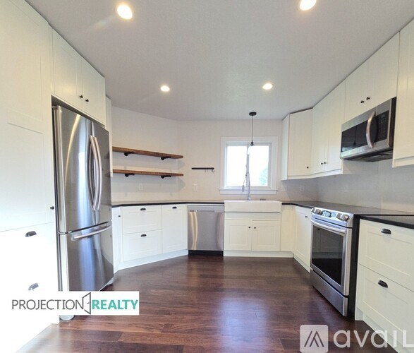 A kitchen with white cabinets and a stainless steel refrigerator.