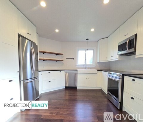 A kitchen with white cabinets and a stainless steel refrigerator.