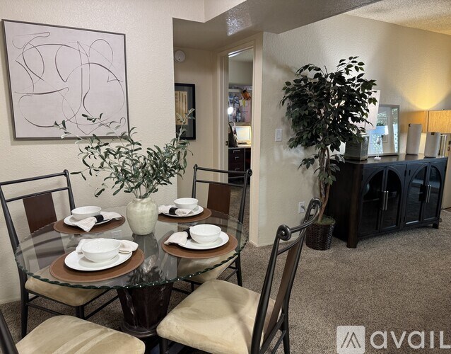 A dining room with a glass table set for four.