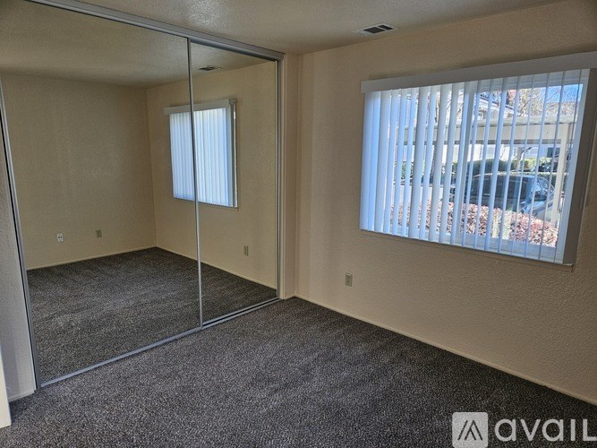 A room with a carpeted floor, a glass door, and a window with blinds.