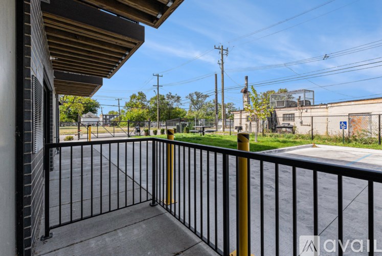 A balcony with a black railing and a yellow post.