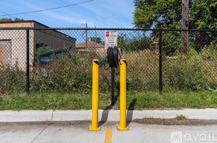 A yellow pole stands in front of a fence with a sign on it.