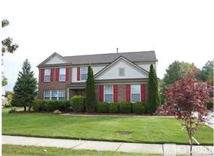 A white house with red trim and a grey roof.