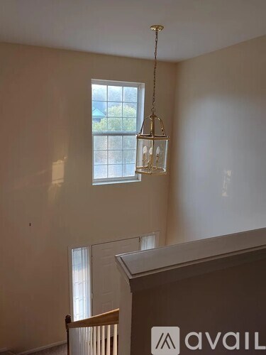 A room with a window and a chandelier hanging from the ceiling.