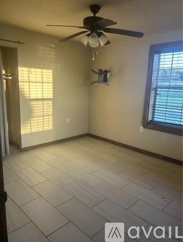 A room with a ceiling fan and a window with blinds.