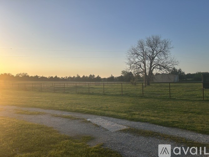 A field with a fence and a tree in the distance.