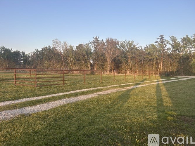 A field with a fence and trees in the background.