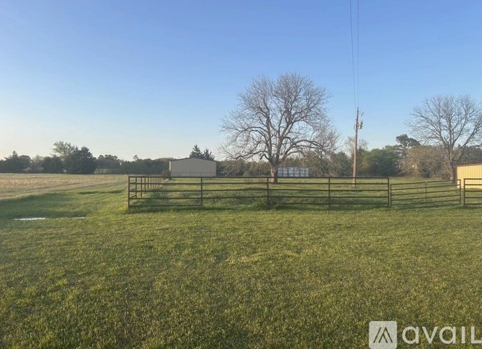 A field with a fence and a building in the background.
