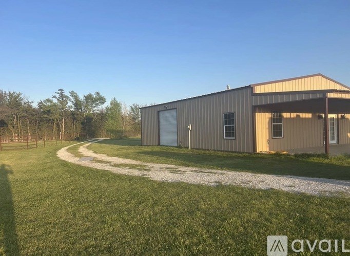 A large metal building with a gravel driveway in front of it.