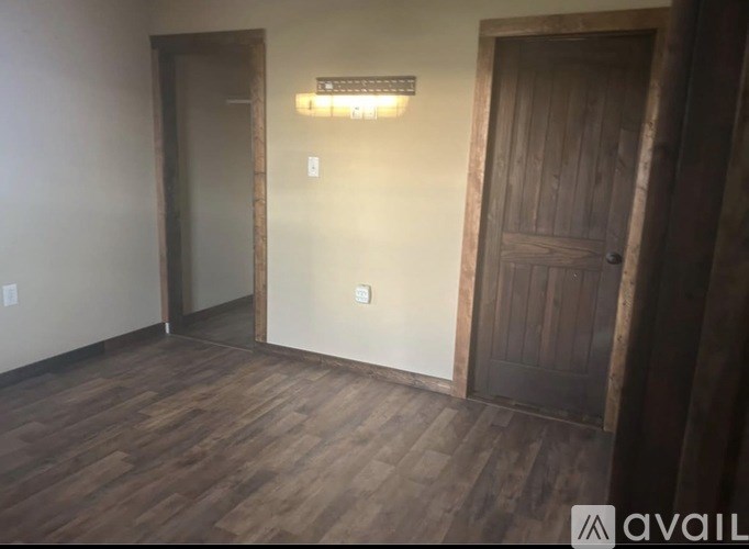 A room with a wooden floor and a door on the right.