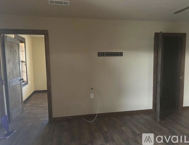 A room with a wooden floor and a door on the left side.