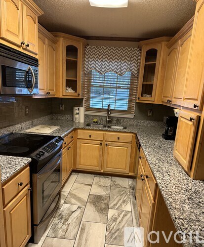 A kitchen with wooden cabinets and a black stove top oven.