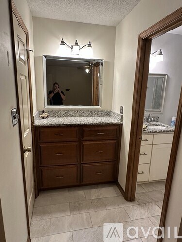 A woman is taking a picture in a bathroom with a large mirror.