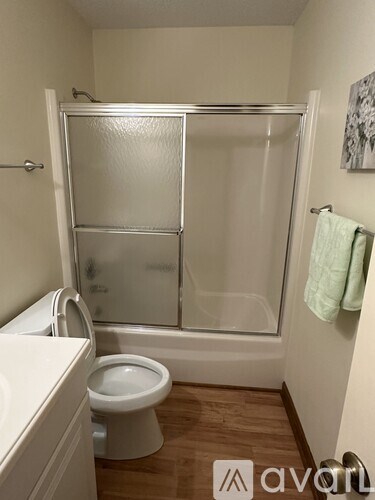 A small bathroom with a toilet, sink and shower.