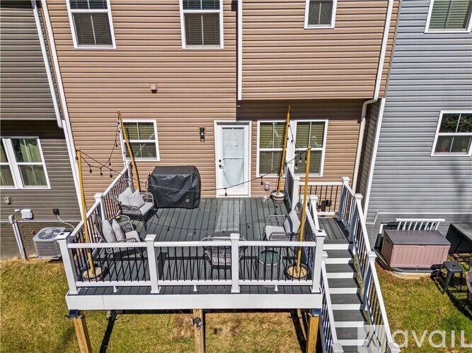 A small deck with a table and chairs is in front of a two-story apartment building.