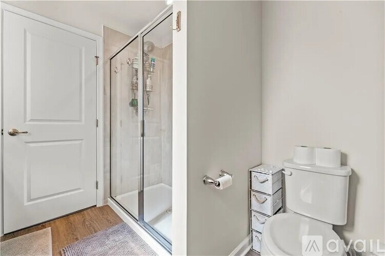 A white bathroom with a toilet and a glass shower door.