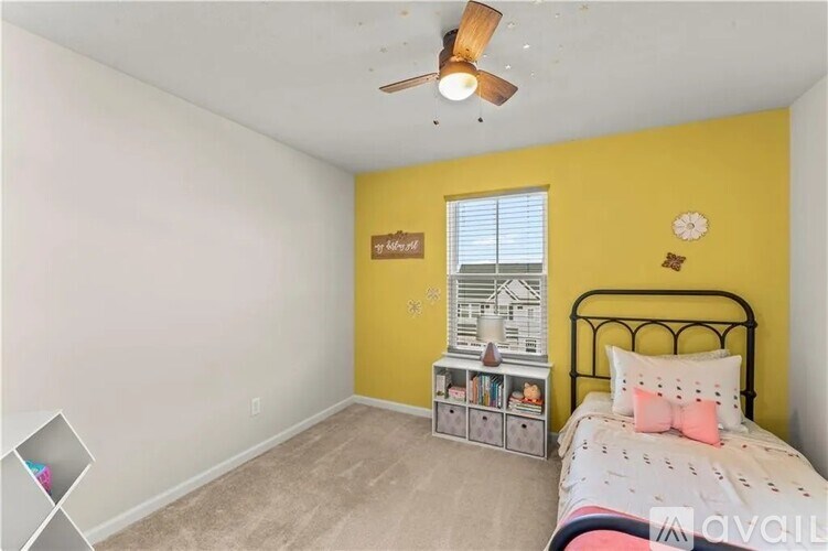 A bedroom with a bed, a fan, and a window with blinds.
