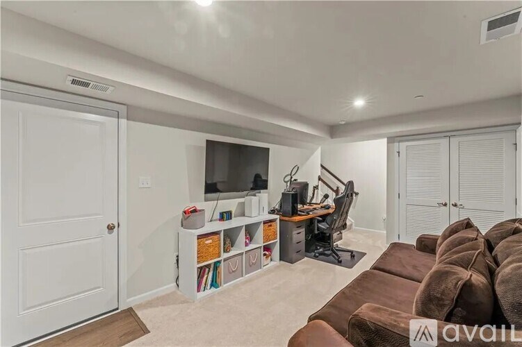 A living room with a brown couch, a white entertainment center, and a white door.