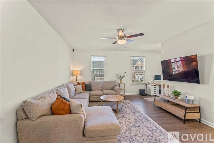 A living room with a grey couch and a ceiling fan.