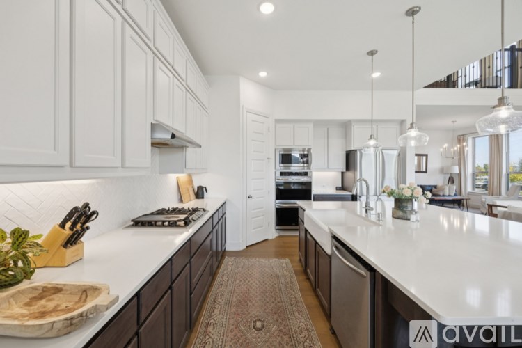 A modern kitchen with white and dark cabinets, a center island, and pendant lights.