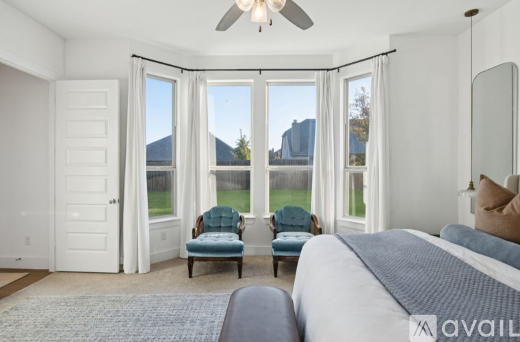 A bedroom with a large bed and a chair in front of a window with a view of a mountain.