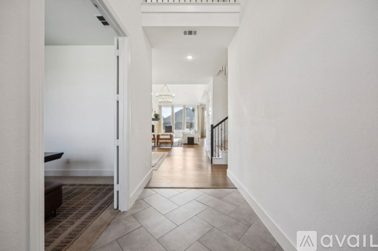 A hallway with a tiled floor and a staircase on the right.