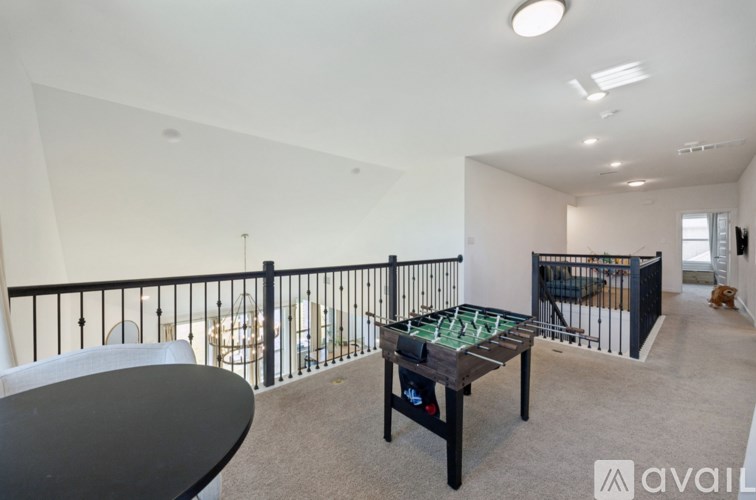 A room with a foosball table and a balcony with a railing.