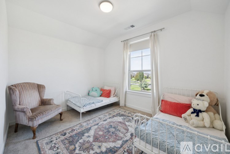 A child's bedroom with a bed, chair, and window.