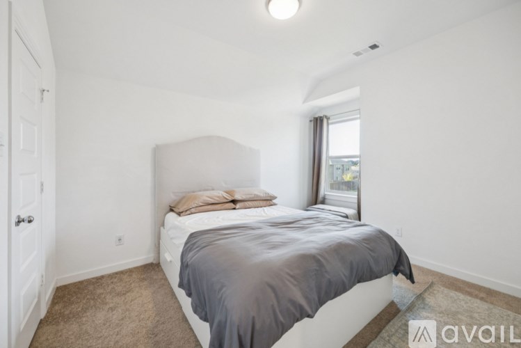 A bedroom with a bed, carpeted floor, and a window.