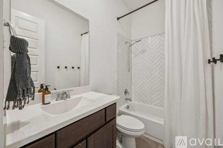 A bathroom with a white sink, toilet, and a shower with a white curtain.