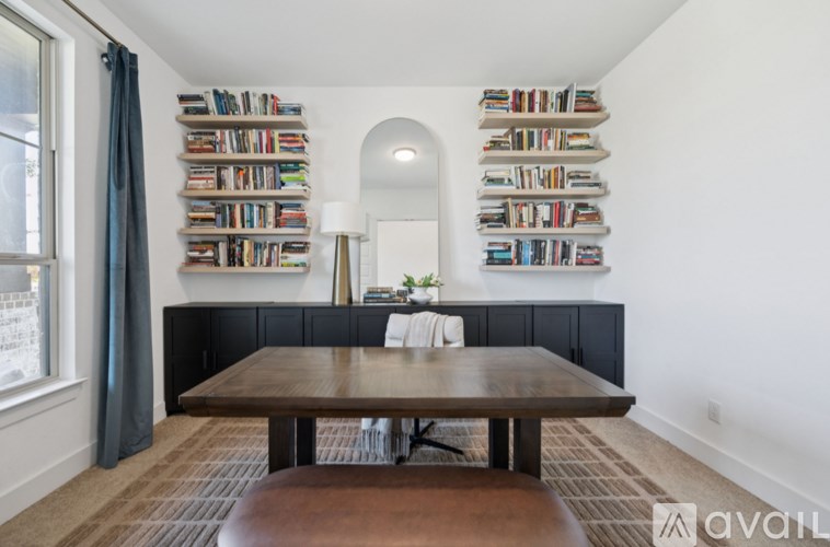 A room with a long table and a bookshelf on the wall.