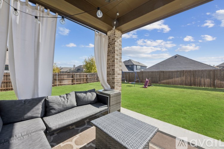 A patio with a grey couch and a table with a glass top.