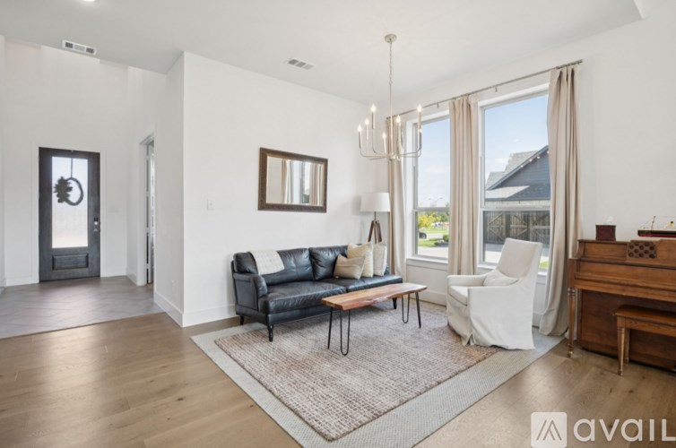 A living room with a black couch, a wooden piano, and a rug on the floor.