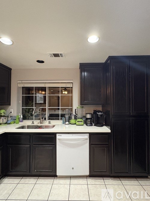A kitchen with a white sink and black cabinets.