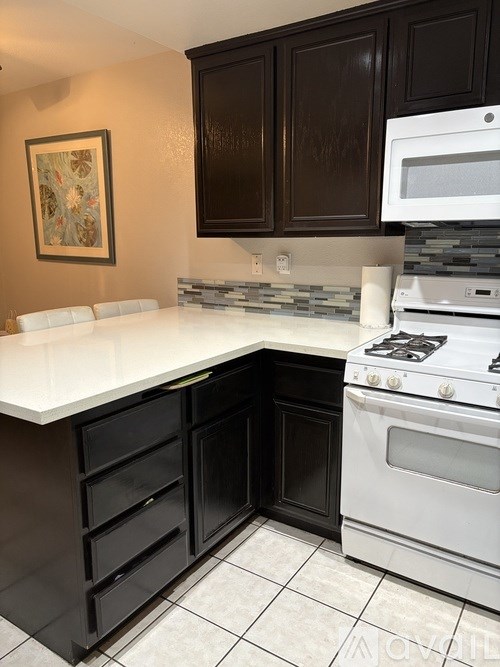 A white countertop with a white oven and black cabinets.