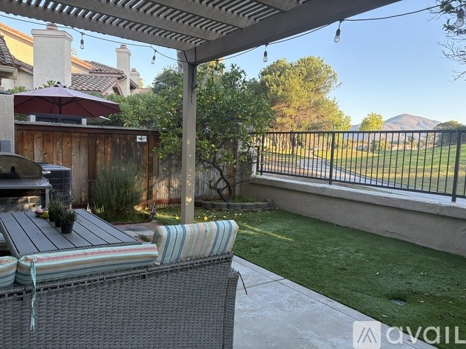 A patio with a striped cushion on a chair and a table under a roof.