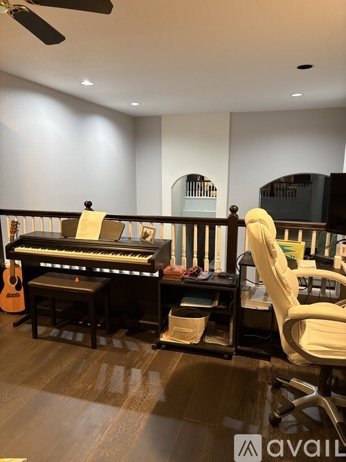 A room with a piano, a chair, and a guitar.