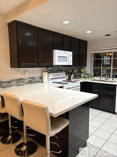 A kitchen with black cabinets and white countertops.