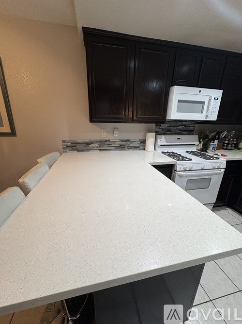 A kitchen with a white countertop and black cabinets.